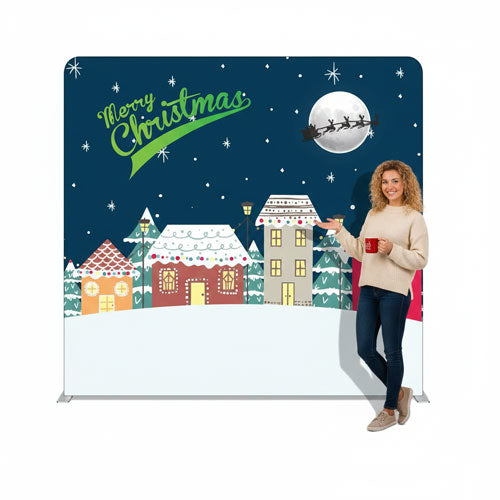 Woman holding a mug in front of a Christmas-themed backdrop with houses and snow.