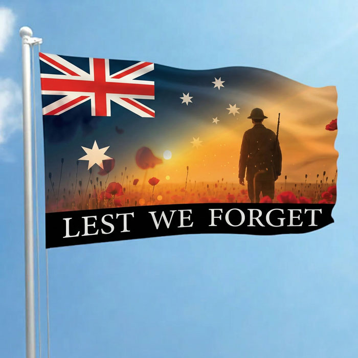 Flag with Australian design, sunset, soldier, and 'Lest We Forget' text against a blue sky.